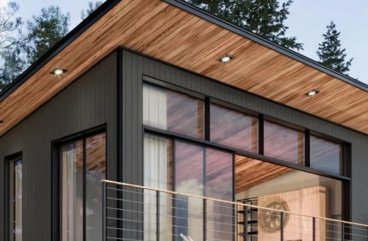 Modern home exterior with dark vertical siding, a wood-clad roof overhang, and covered deck